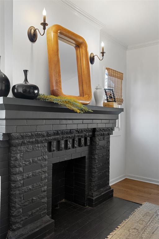 room details featuring ornamental molding, a fireplace, baseboards, and wood finished floors