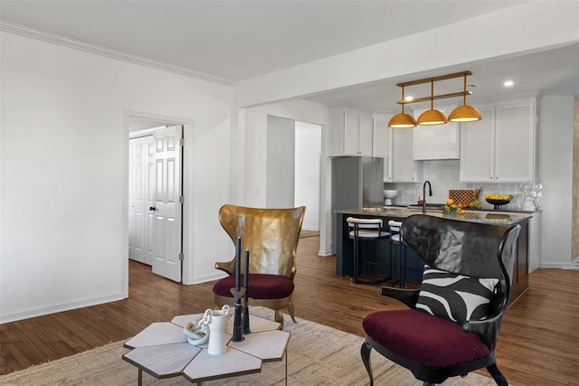 living area with dark wood-type flooring, recessed lighting, crown molding, and baseboards