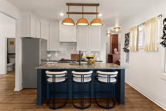 kitchen with backsplash, freestanding refrigerator, and white cabinets