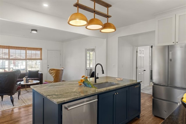 kitchen featuring dark wood-style floors, dark stone countertops, stainless steel appliances, and a sink