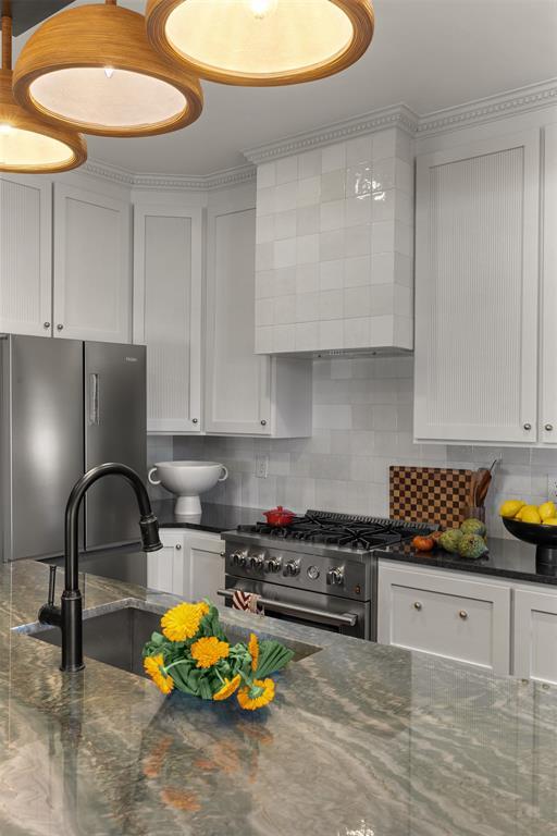 kitchen featuring white cabinets, a sink, stainless steel appliances, and backsplash