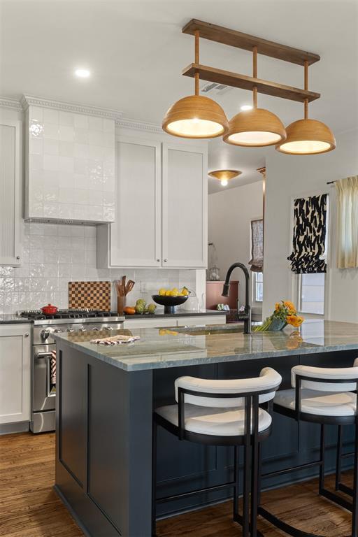 kitchen featuring high end stainless steel range oven, tasteful backsplash, a kitchen bar, and dark wood-style floors