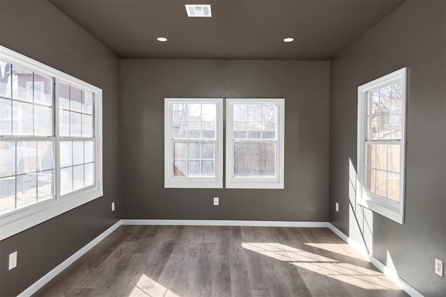 empty room with baseboards, visible vents, wood finished floors, and recessed lighting