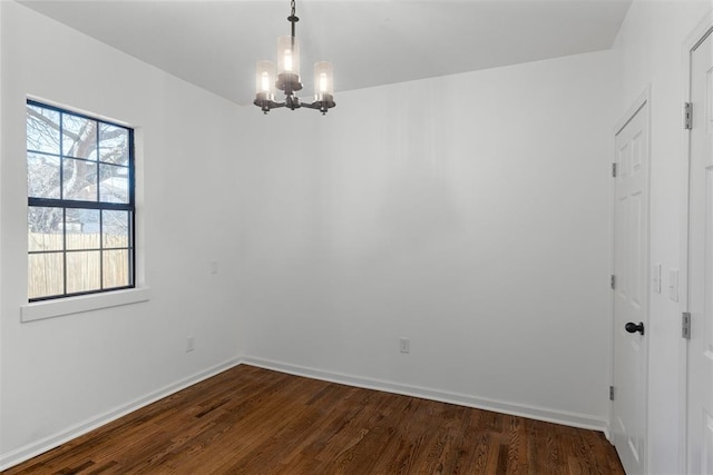 unfurnished room featuring baseboards, dark wood-type flooring, and a notable chandelier