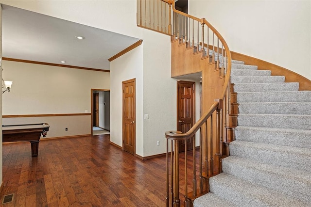 stairway with ornamental molding, baseboards, visible vents, and hardwood / wood-style floors