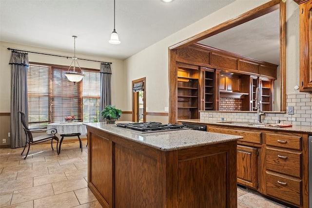 kitchen featuring a kitchen island, light stone countertops, stainless steel gas stovetop, open shelves, and a sink