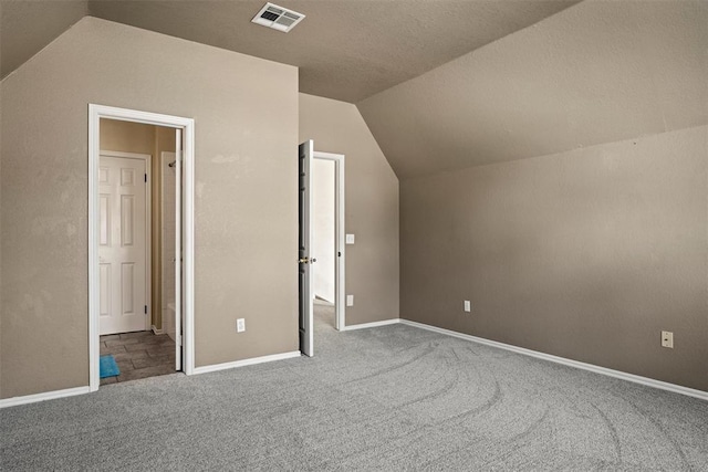 additional living space with carpet, visible vents, vaulted ceiling, and baseboards