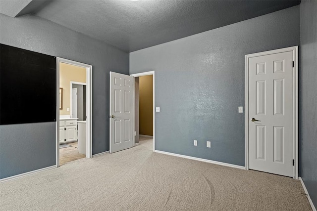 unfurnished bedroom featuring light carpet, a textured wall, a textured ceiling, and baseboards