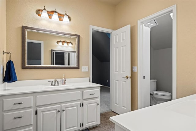 bathroom with toilet, a textured wall, and vanity