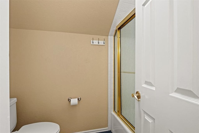 bathroom featuring toilet, baseboards, and bath / shower combo with glass door