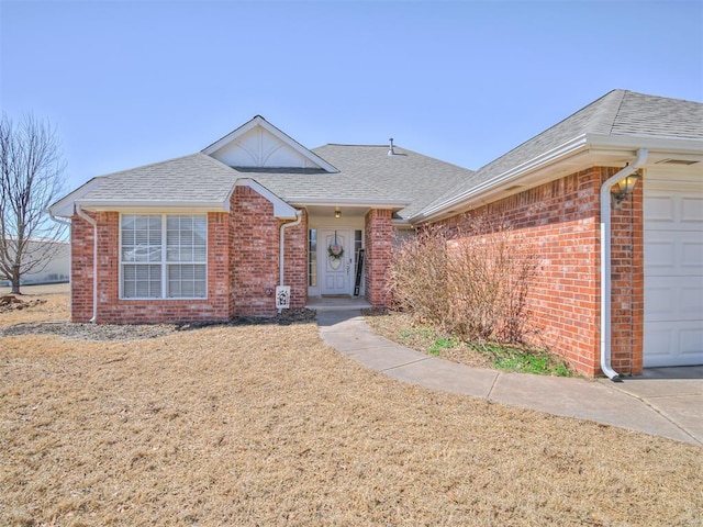 ranch-style house with brick siding, an attached garage, and roof with shingles