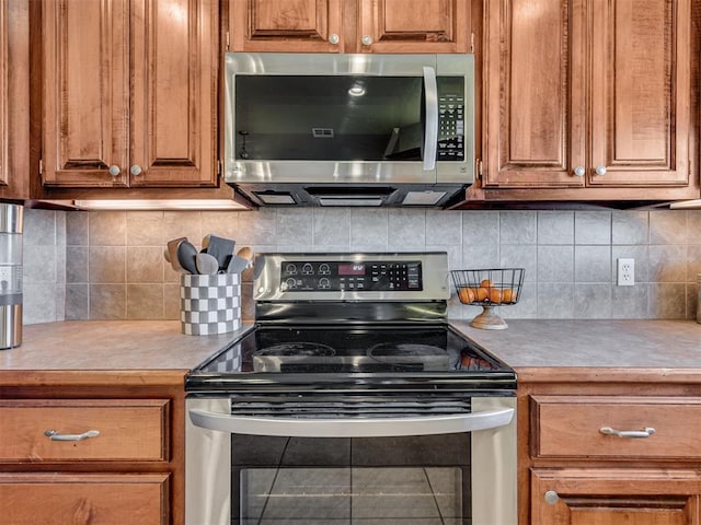 kitchen featuring brown cabinetry, appliances with stainless steel finishes, light countertops, and decorative backsplash