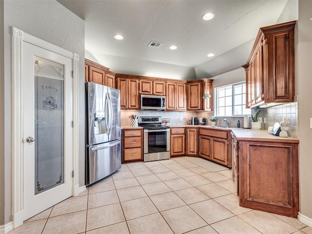 kitchen with light tile patterned floors, stainless steel appliances, visible vents, light countertops, and decorative backsplash