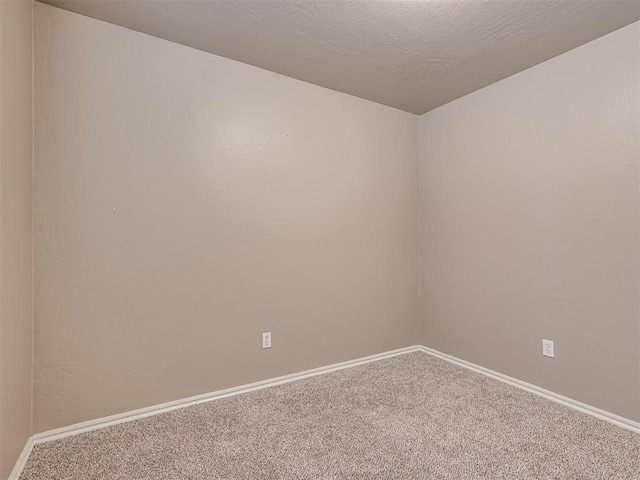 unfurnished room with a textured ceiling, carpet, and baseboards