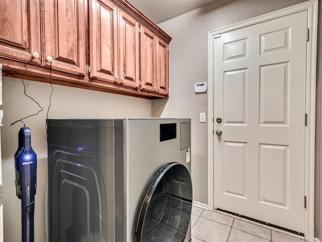 laundry room featuring light tile patterned floors, a textured wall, and cabinet space