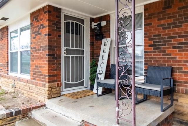 entrance to property with covered porch and brick siding