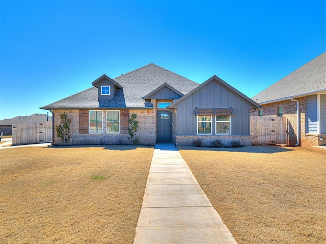 view of front of home featuring a gate, fence, a front yard, board and batten siding, and brick siding