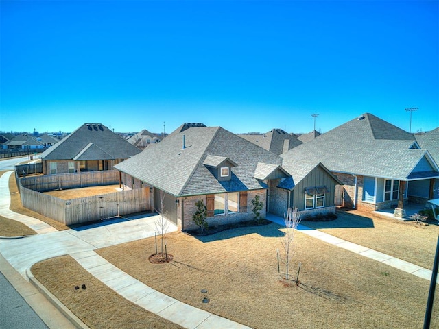 view of front of house featuring a shingled roof, board and batten siding, fence, driveway, and a front lawn