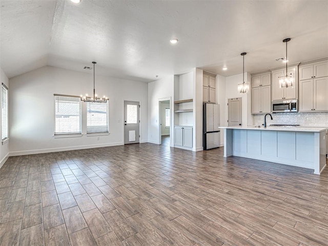 kitchen featuring stainless steel appliances, wood finished floors, open floor plan, light countertops, and an inviting chandelier