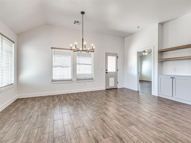 unfurnished dining area featuring ceiling fan with notable chandelier, wood finished floors, visible vents, baseboards, and vaulted ceiling