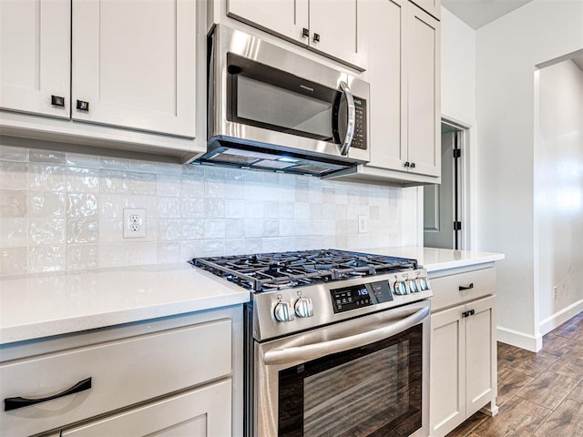 kitchen featuring baseboards, light wood-style flooring, stainless steel appliances, light countertops, and backsplash