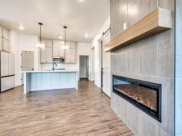 kitchen featuring a barn door, stainless steel microwave, white refrigerator, a fireplace, and backsplash