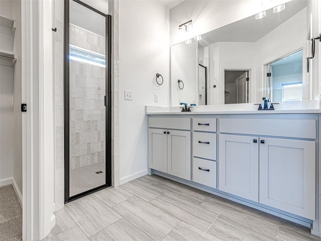 full bath featuring a stall shower, a sink, baseboards, and double vanity