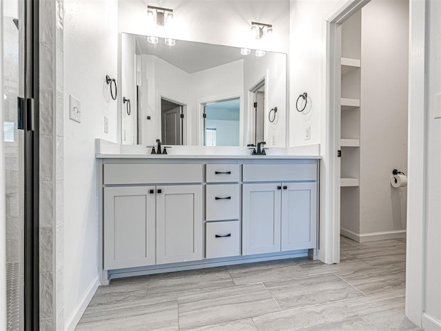 full bath with double vanity, a sink, and baseboards