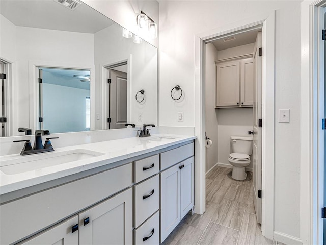 full bathroom with visible vents, double vanity, a sink, and toilet