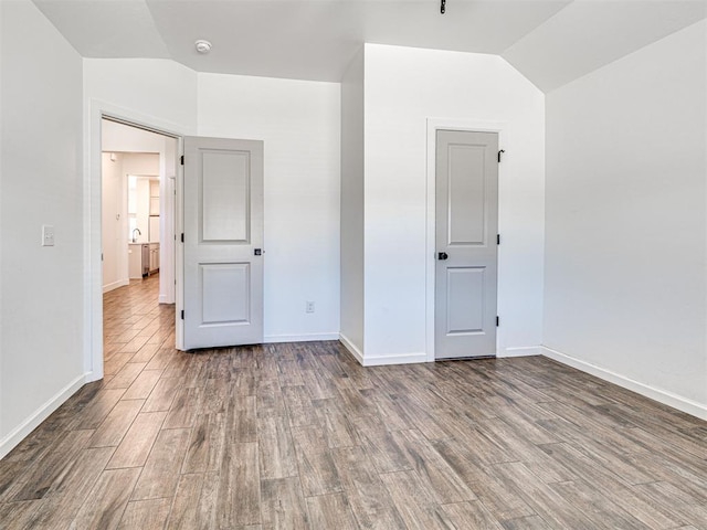 unfurnished bedroom with vaulted ceiling, wood finished floors, and baseboards