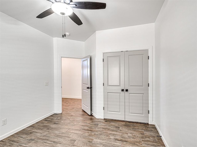 unfurnished bedroom featuring a closet, ceiling fan, baseboards, and wood finished floors