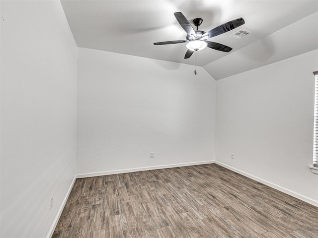 unfurnished room with visible vents, vaulted ceiling, baseboards, and wood finished floors