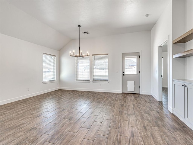 unfurnished dining area with a notable chandelier, visible vents, dark wood-type flooring, vaulted ceiling, and baseboards