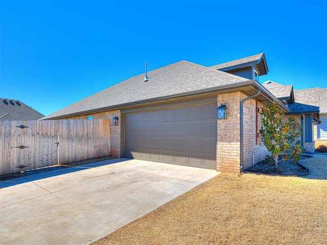 view of side of home with a shingled roof, brick siding, fence, and an attached garage