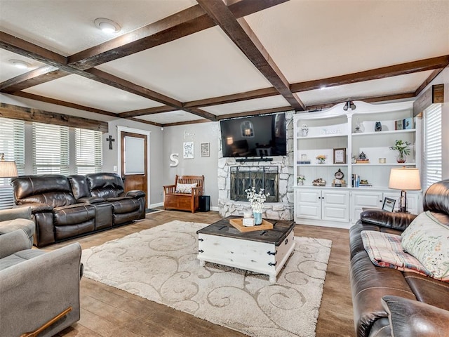 living area with a stone fireplace, beamed ceiling, coffered ceiling, and wood finished floors