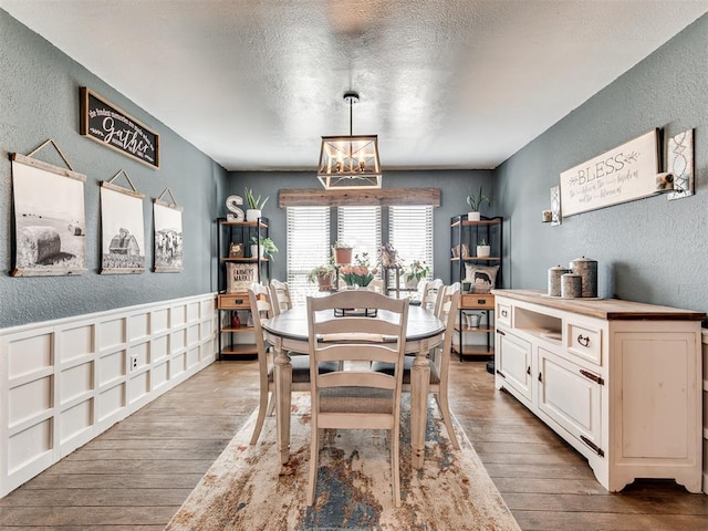 dining room featuring wood-type flooring and a textured wall