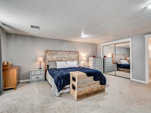 carpeted bedroom with a closet, visible vents, a textured ceiling, and baseboards