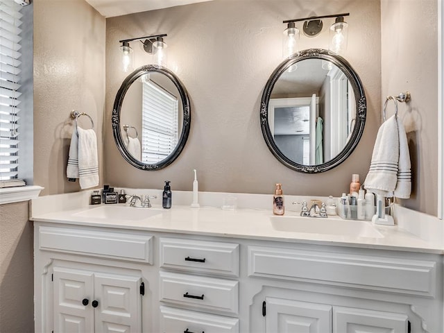 full bath with a textured wall, a sink, and double vanity