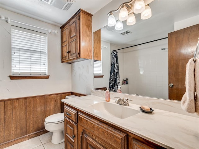 bathroom featuring tile patterned flooring, toilet, a wainscoted wall, wood walls, and visible vents