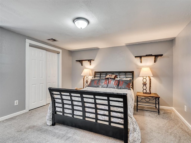 carpeted bedroom featuring baseboards, a closet, visible vents, and a textured ceiling