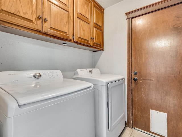 washroom featuring light tile patterned flooring, washing machine and clothes dryer, and cabinet space