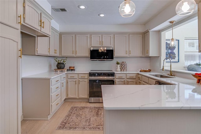 kitchen featuring visible vents, light wood-style flooring, appliances with stainless steel finishes, a peninsula, and a sink