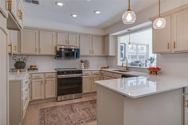 kitchen with electric range, a sink, stainless steel microwave, light wood-style floors, and a peninsula