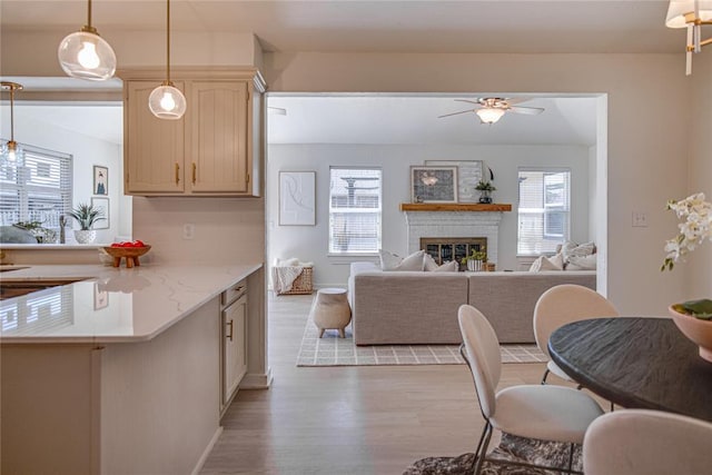 kitchen with a brick fireplace, decorative light fixtures, open floor plan, decorative backsplash, and light wood-style flooring