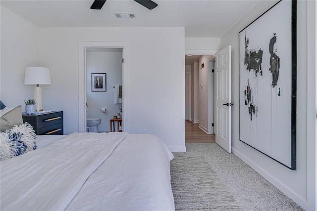 carpeted bedroom featuring visible vents, ceiling fan, ensuite bathroom, and baseboards