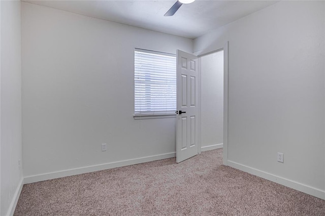 carpeted empty room with baseboards and a ceiling fan