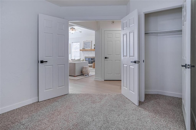 unfurnished bedroom featuring carpet, baseboards, a closet, and a large fireplace