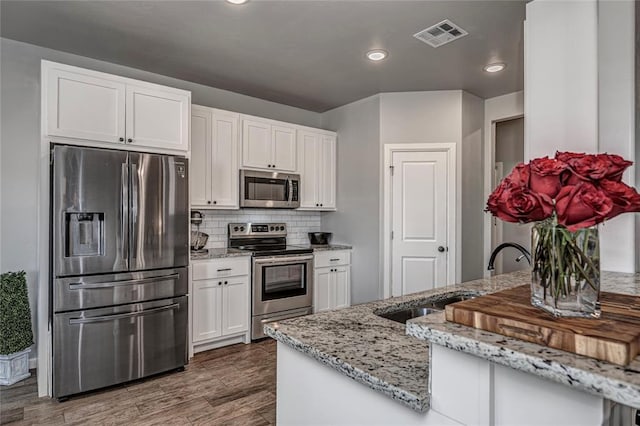 kitchen featuring stainless steel appliances, tasteful backsplash, visible vents, white cabinets, and a sink