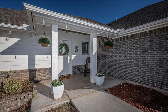 view of exterior entry with a shingled roof