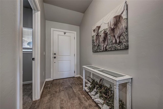 doorway featuring lofted ceiling, baseboards, and wood finished floors